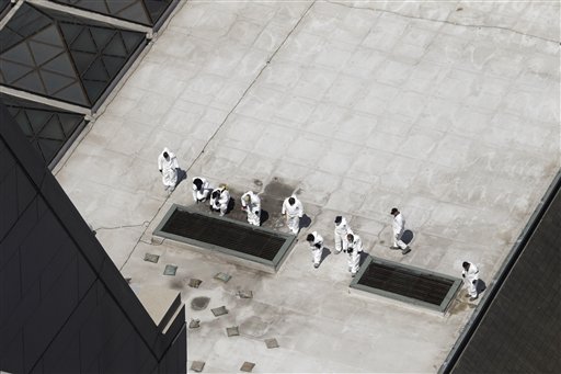 Investigators on Thursday inspect the roof of a building across the street from the area where a bomb exploded near the Boston Marathon finish line,