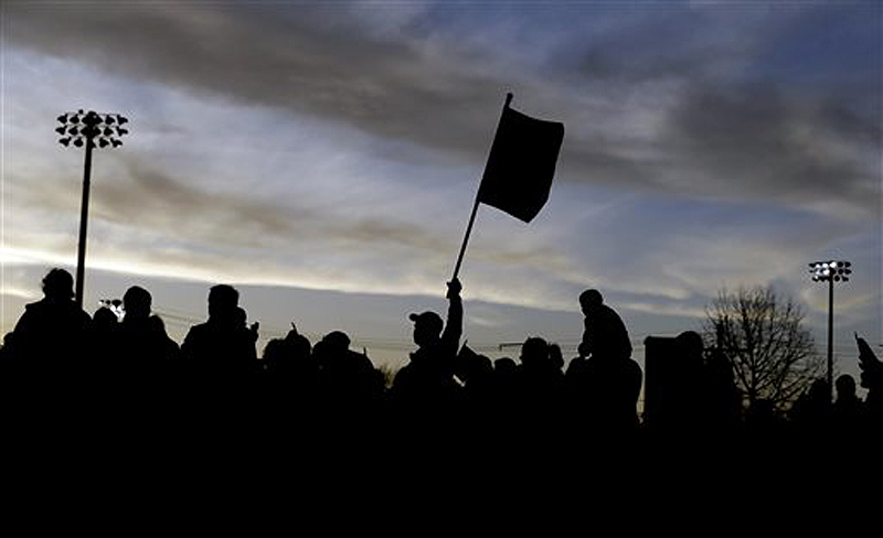 Al Ghoughasian, 50, center, raises a U.S. flag during a vigil for the victims of the Boston Marathon bombing Saturday in Watertown, Mass. Suspected bomber Dzhokhar Tsarnaev is hospitalized in serious condition with unspecified injuries after he was captured in an all day manhunt the day before.