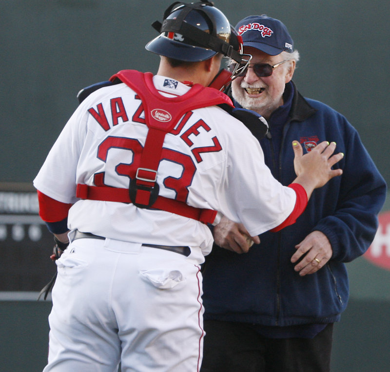 Catcher Christian Vazquez congratulates former Hadlock Field announcer Dean Rogers after Rogers’ ceremonial first pitch. The Dogs got their season off to a slow start, losing 13-5.