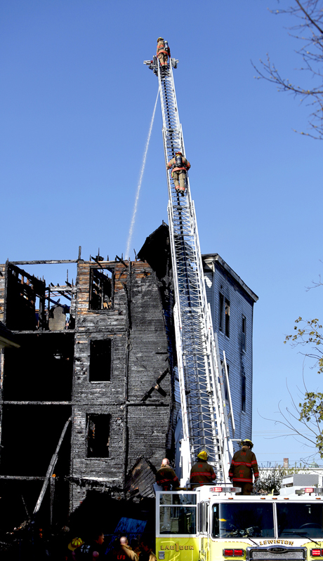 Firefighters spray water on what's left of the roof of a vacant apartment building on Bartlett Street in Lewiston on Monday.