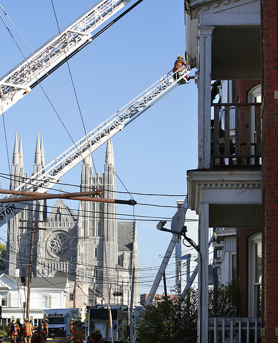 A firefighter checks for hot spots on the front of a vacant apartment building on Bartlett Street in downtown Lewiston on Monday.