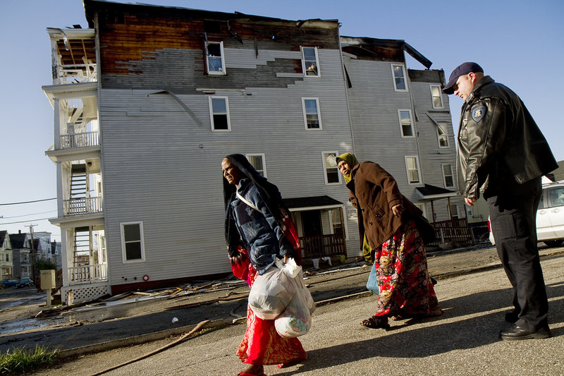 Lewiston police Officer Nick Wiers keeps displaced residents away from the scene of a fire Saturday. Many of the newly homeless people were members of Lewiston’s Somali community.