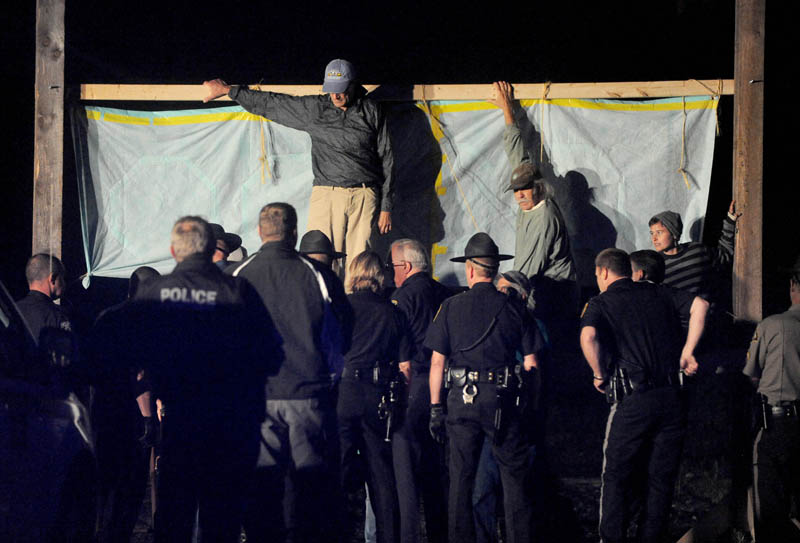 Authorities approach members from 350 Maine, who blocked the railroad crossing at Lawrence Avenue in Fairfield Thursday night, to protest the transport of fracked oil.