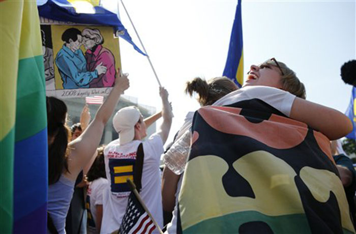 Sharon Burk, left, and Molly Wagner, right, students from American University, embrace in front of the Supreme Court after the court struck down a federal provision denying benefits to legally married gay couples.