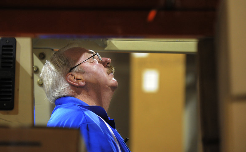 Bob Prescott looks up as he aligns his forklift at his new job for Distributor Corp. of New England in Westbrook. Prescott was laid off by Hostess late last year.