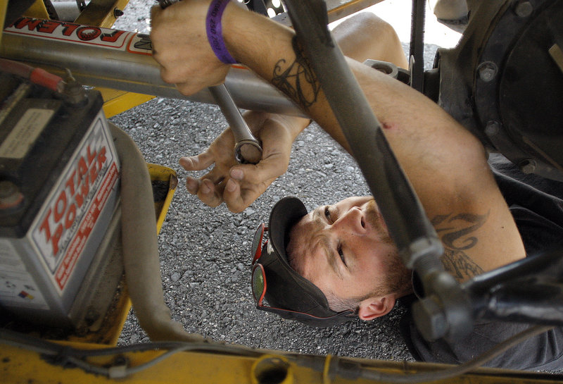 Ben Clark of Whitney contorts to find wrench room under Michael Landry’s car as he preps the vehicle before the start of the TD Bank 250 on Sunday.