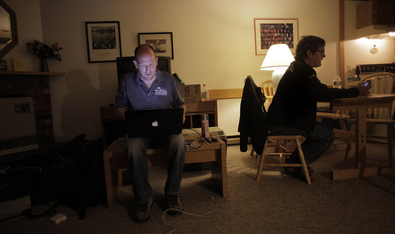 John Cassidy, left, goes over racing footage from the first day of the New England Forest Rally in Newry as co-driver Dave Getchell checks his phone before going to bed.