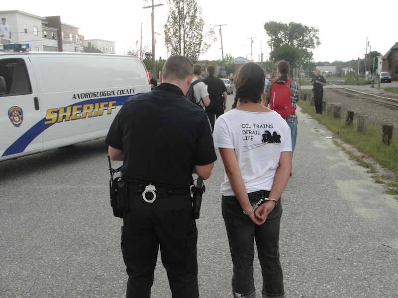 Three people were arrested Wednesday, Aug. 28, 2013 after staging an oil-train protest on railroad tracks in downtown Auburn. The back of one of the protestors' shirts says, "Oil trains derail life."