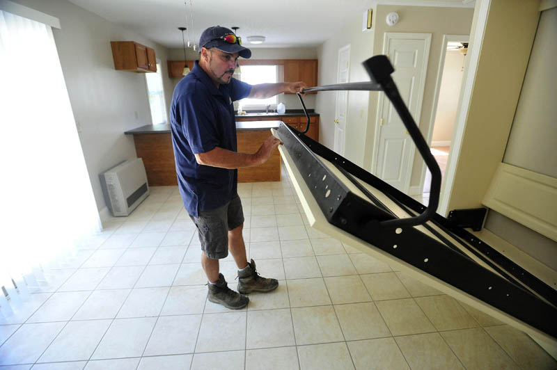 Andy Vear demonstrates how the Murphy bed pulls out to accommodate guests in the combined kitchen, dining and living area at the 20 Cool St. micro-home in Waterville. The main bedroom is through the door to the right and next to that is a full bathroom.