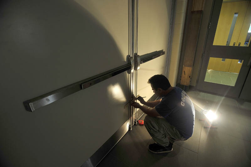 Jesse Donovan, from Donovan Co., installs doors in the new hallway at the entrance of Mt. Blue Learning Campus in Farmington today.