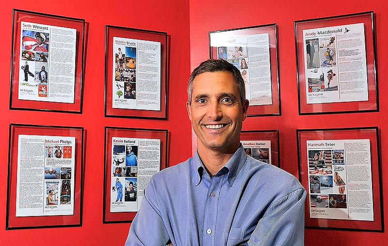 Peter Carlisle stands in front of a gallery of his clients in his office at the MHG Ice Centre in Saco. He said when he started his own agency in 1997, he considered the growing popularity of action sports, such as snowboarding, and saw opportunity. “He was a visionary,” says his brother, Jeff Carlisle.