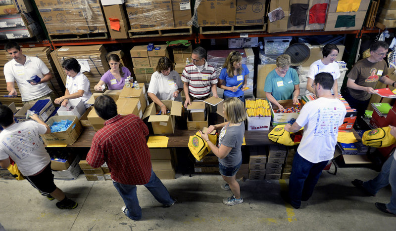 Unum volunteers stuff backpacks for needy students at Ruth's Reusable Resources in Portland on Wednesday, August 14, 2013.