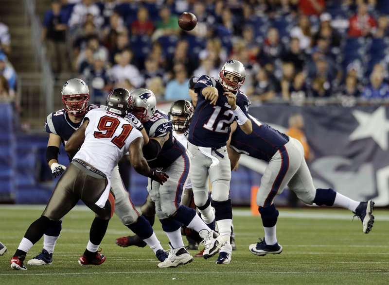 New England’s Tom Brady, showing no ill effects of a sore knee, throws a touchdown pass over Tampa Bay defensive end Da’Quan Bowers to new receiver Danny Amendola during a 25-21 preseason win on Friday.