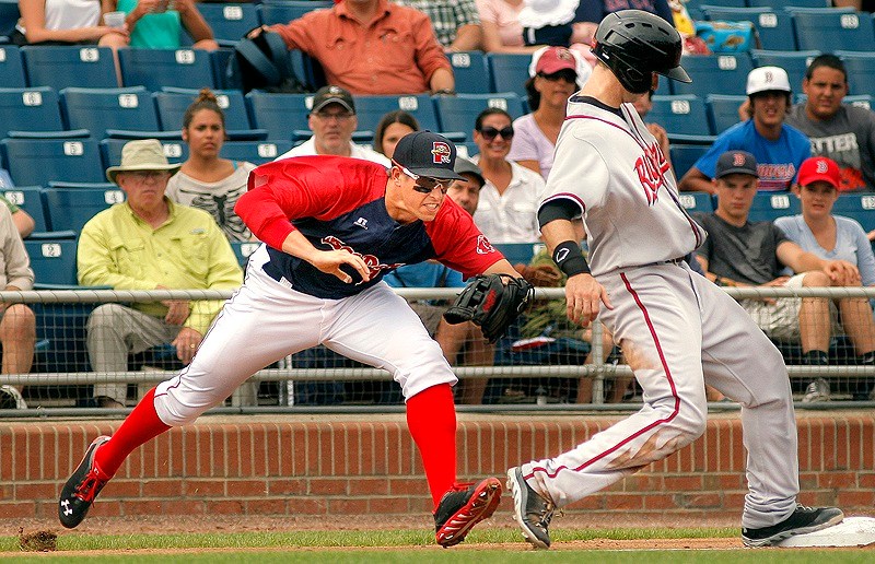 Third baseman Garin Cecchini of the Portland Sea Dogs swipes at Ryan Lollis of the Richmond Flying Squirrels, who hustled back after advancing on a single.