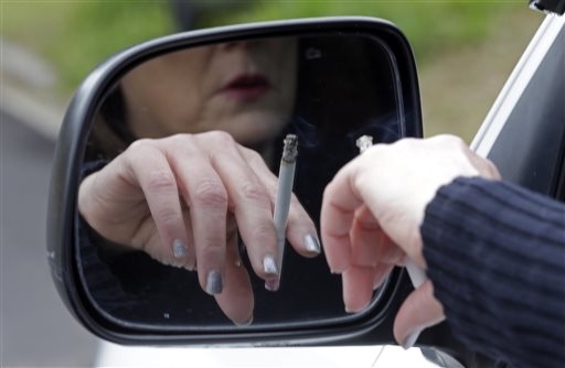 FILE - In this Saturday, March 2, file 2013 photo, a woman smokes a cigarette while sitting in her truck in Hayneville, Ala. The federal health care law requires insurers to accept all applicants regardless of pre-existing medical problems. But it also allows them to charge smokers premiums that are up to 50 percent higher than those offered non-smokers - a way for insurers to ward off bad risks. (AP Photo/Dave Martin)