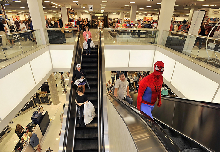 Shoppers take the down escalator with bags of purchases while a costumed Spider-Man heads up to the children's department on the second floor as Bon-Ton holds its grand opening at the Maine Mall on Thursday.