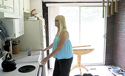 In this July 2013 file photo, Winslow resident and MaineCare recipient Judith Mitchell, who sees very little, feels for a glass of water in her kitchen on Tuesday. Mitchell said she had been trying for three weeks to get transportation for an eye doctor appointment in Ellsworth. Lawmakers said Thursday, Sept. 13, 2013 that they are keeping pressure on the companies that arrange rides for MaineCare recipients in an effort to improve the service