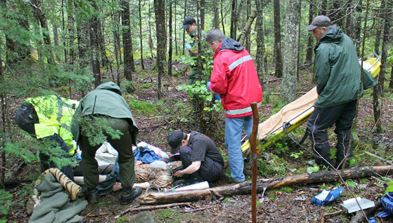 Maine Warden Service Chaplain Kate Braestrup crouches on the ground next to 86-year-old Arthur Wakeman after he was found about 1.2 miles from his Benton home Friday.