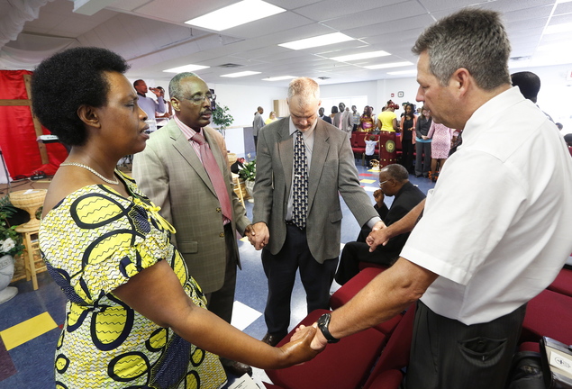 Senior Pastor Peter Mutima, second from left, prays with other church leaders during a Sunday service.