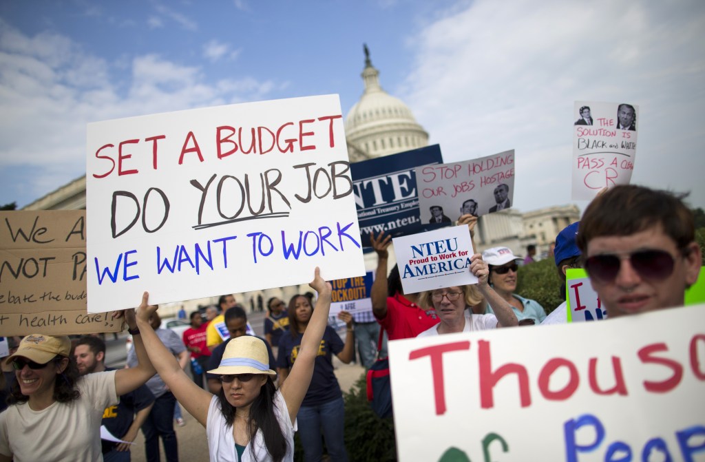 Protesters hold signs during an event with the Democratic Progressive Caucus and furloughed federal employees on Capitol Hill in Washington on Friday as the budget battle continued.