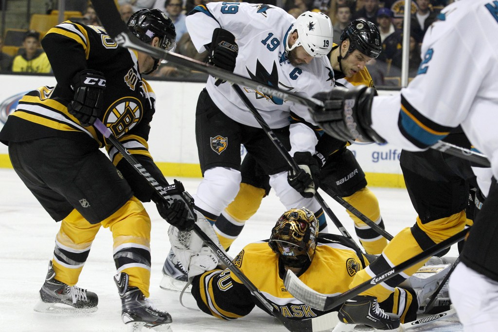 Tuukka Rask of the Boston Bruins makes a save while lying on his back Thursday night as Joe Thornton of the San Jose Sharks attempts to get a stick on the puck in the first period of the Bruins’ 2-1 victory.