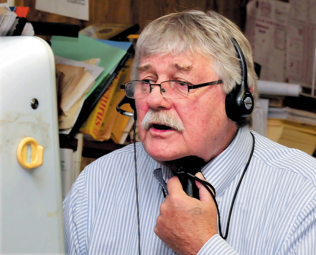 Morning Sentinel reporter Doug Harlow speaks on the phone while using an electronic voice box device.