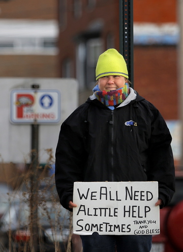 Cheree Theriault, who stays at the Florence House for homeless women, panhandles Tuesday in the median at the corner of Congress and St. John streets in Portland.