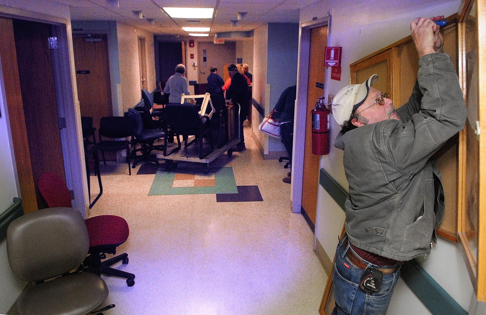 Paul Marcotte unscrews a display case from the wall during the public sale of items Saturday from the former MaineGeneral Medical Center on East Chestnut Street in Augusta.
