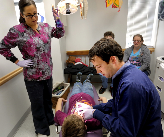 Dr. Michael Dowling works on Aiden Serber, 8, of Westbrook, as dental hygenist Trisha Drewry assists at Falmouth Pediatric Dentistry in Falmouth.