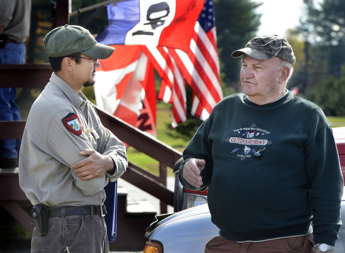 Kyle Ravana, left, Maine’s new head deer biologist, talks with hunter Floyd Whitmore at a moose tagging station in Solon last month. In his first seven months on the job Ravana is proving a good listener.