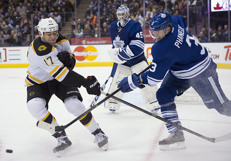 Toronto Maple Leafs defenseman Dion Phaneuf (3) clears the puck past Boston Bruins left winger Milan Lucic (17) as goaltender Jonathan Bernier looks on during first period NHL action in Toronto on Sunday Dec. 8, 2013. (AP Photo/The Canadian Press, Frank Gunn) Canada;hockey;NHL;athlete;athletes;athletic;athletics;Canadian;c