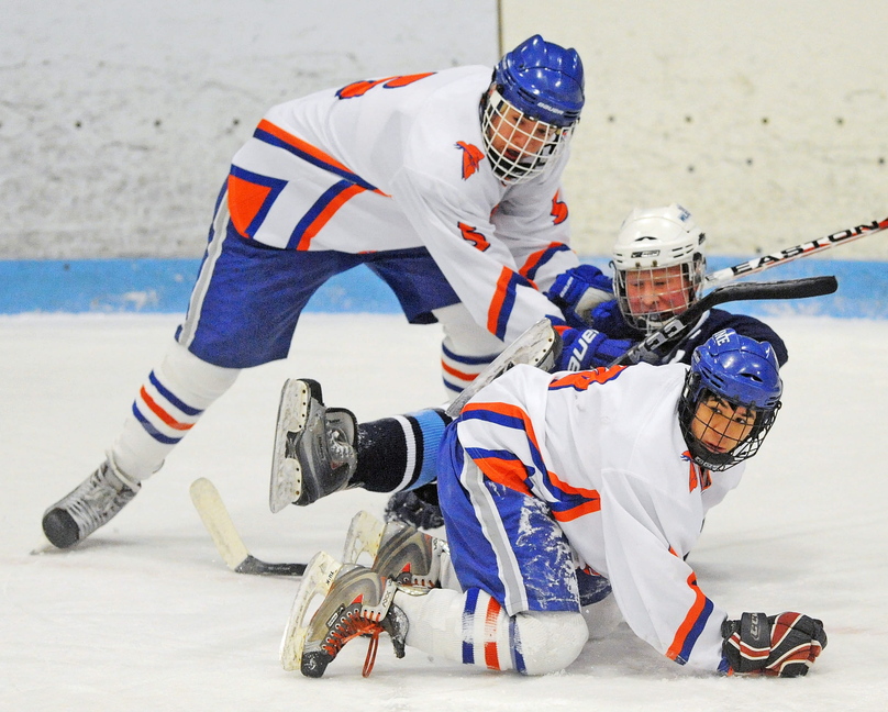 TIGHT QUARTERS: Lawrence/Skowhegan’s Adam Littlefield, back, and teammate Anthony Paul (9) sandwich Presque Isle’s Tyler Seely during the first period of their game Friday at Sukee Arena in Winslow.