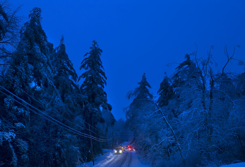 Utility crews prepare to work on power lines at dusk Thursday in Litchfield, where many have been without electricity since Monday's ice storm.