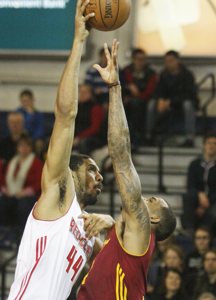 Zeke Marshall, left, of the Red Claws reaches high over Gilbert Brown of the Canton Charge as he takes a shot during Maine’s 110-105 win Thursday at the Portland Expo.