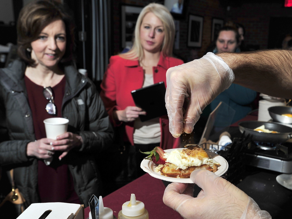 Catherine Dascanio, left, Portland, and Erica Archer of Scarborough await their freshly prepared Pork Belly Waffle with egg sunny-side-up with Maple Bacon Crunch sprinkled by Eve’s Chef Tim Labonte, who won this year’s Incredible Breakfast Cook-Off.