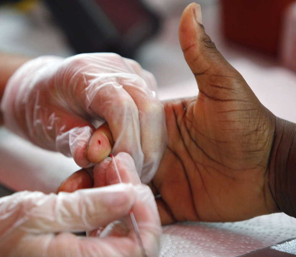 A medical technician draws a blood sample to screen for glucose and cholesterol.