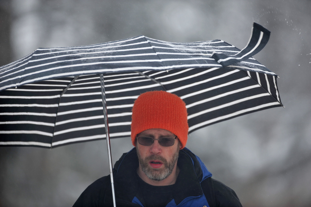 SPRING STORM: John Ervim walks along Mayflower Hill Drive on his way to work at Colby College as rain falls in Waterville on Thursday.