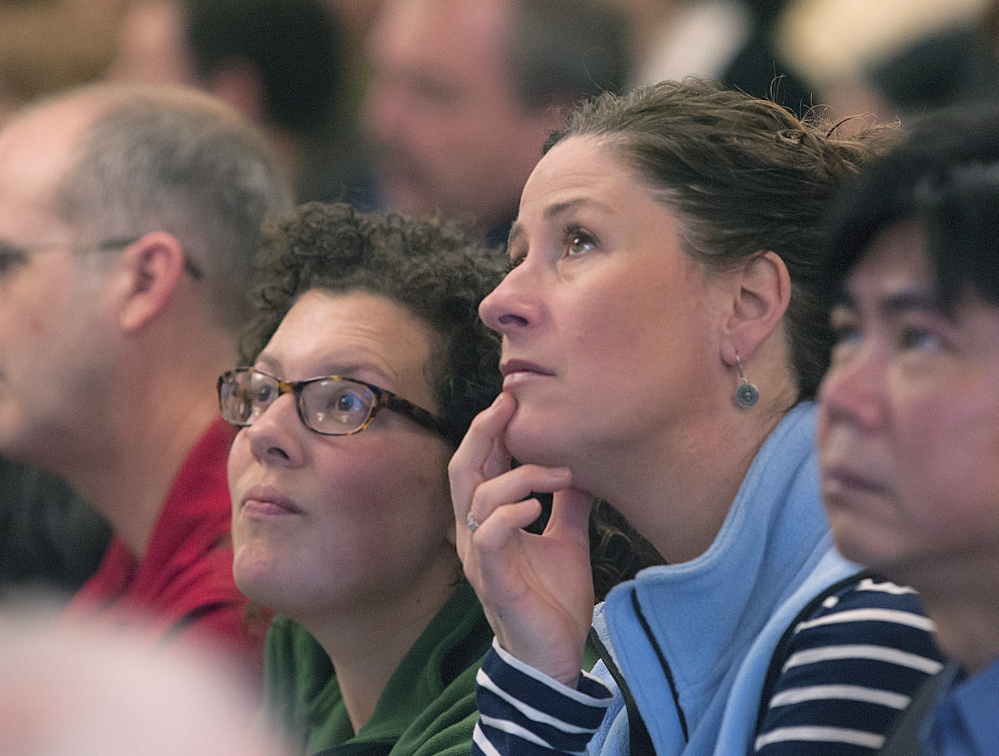 University of Maine employees Erin Straine, left, and Faith Erhardt of the College of Education and Human Development in Orono digest the figures presented on an overhead display during a budget presentation to employees at the Wells Conference Center on Friday.