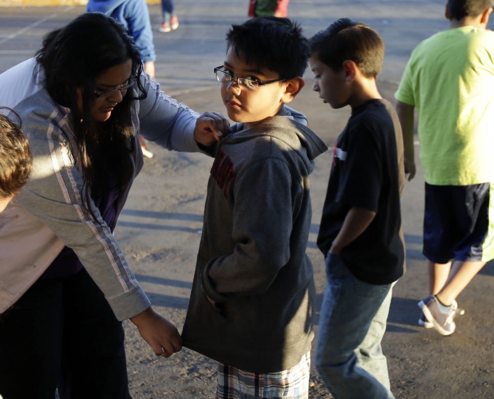 Marina Beltran zips up the jacket of her son Antonio before he takes part in the running program.