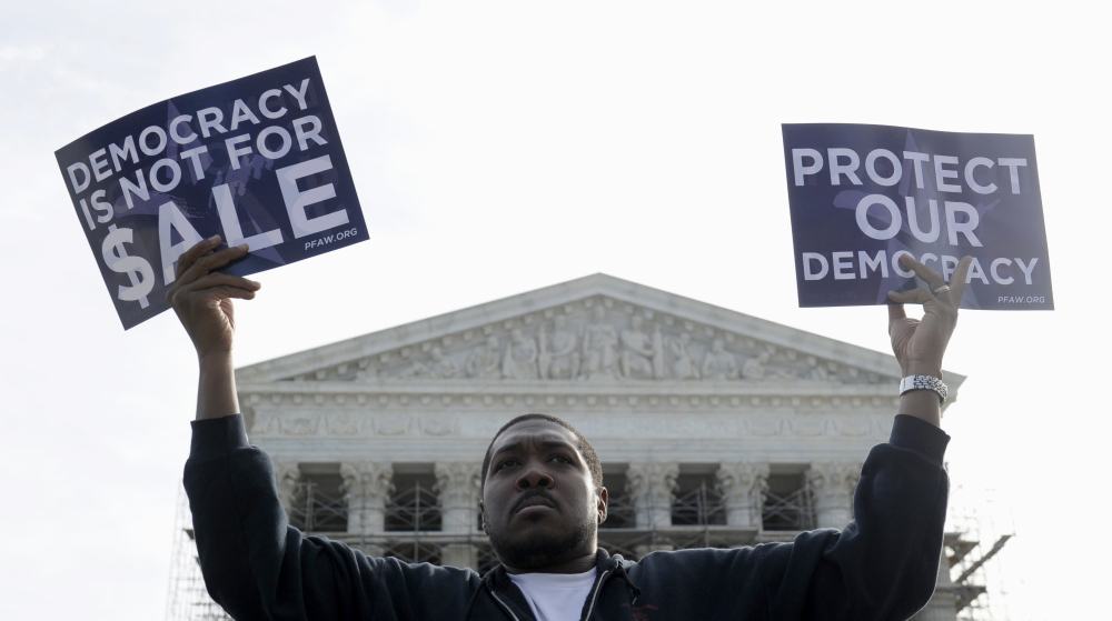 Cornell Woolridge of Windsor Mill, Md., takes part in a demonstration outside the Supreme Court in Washington last fall when the court heard arguments on campaign finance. The Supreme Court struck down limits Wednesday in federal law on the overall campaign contributions the biggest individual donors may make to candidates, political parties and political action committees.
