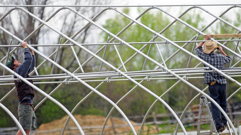 Kevin Leavitt, left, and Brendan Shea assemble a high tunnel greenhouse last month at a Monmouth horse farm where Leavitt rents a field and grows vegetables for his Farmer Kevâs Organic business. Leavitt said he would use the greenhouse to grow cucumbers and tomatoes for his CSA clients and customers at farmers markets.