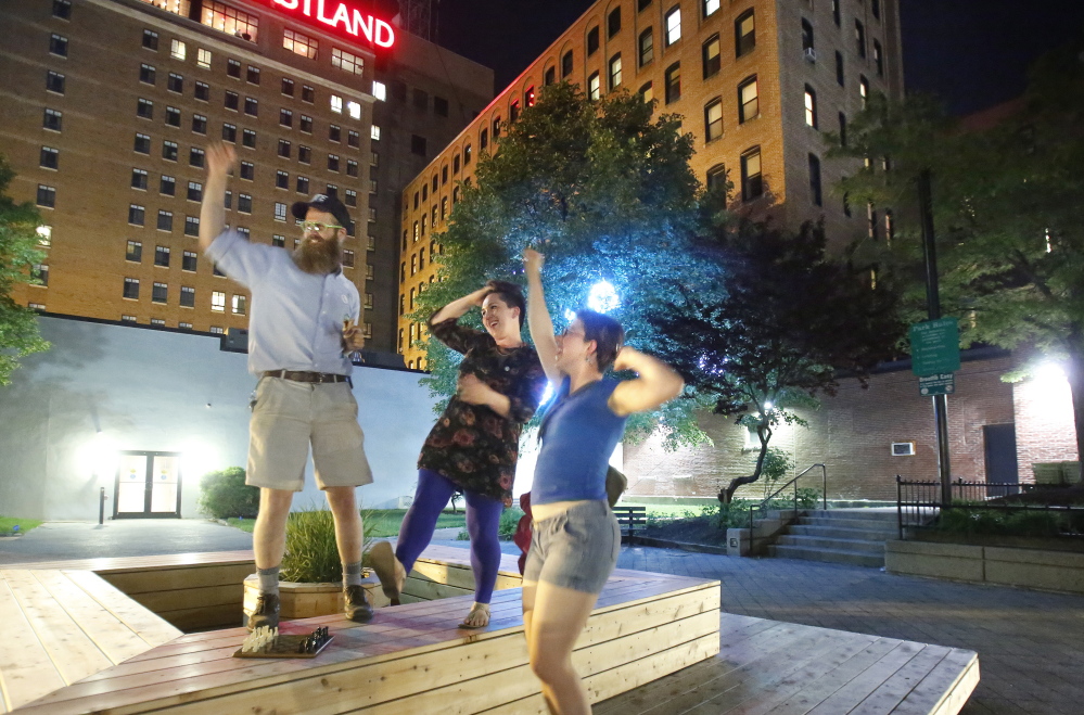 Yes on 1 campaign volunteers Asher Platts, left, and Becky Wartell, right, and Lauren Besanko, a campaign staffer, dance in Congress Square Plaza on Tuesday. The “very close vote” blocked the sale of the park, but also had far broader implications for city-owned land. Gregory Rec/Staff Photographer