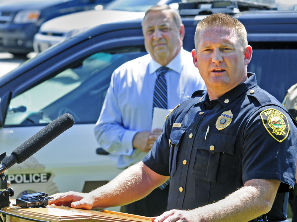 Gov. Paul LePage listens Tuesday as Augusta Deputy Police Chief Jared Mills talks during an Augusta news conference called to announce a drop in the state crime rate in 2013.