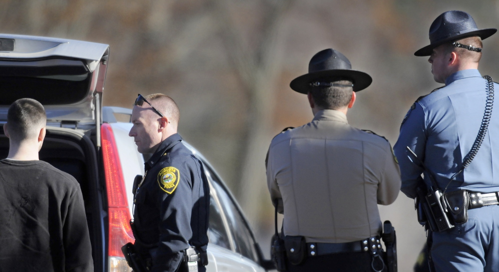 Augusta Police Lt. Kevin Lully, second from left, speaks with a man after a robbery at Shaw’s in Augusta. The man was not held. The number of robberies declined in 2013.