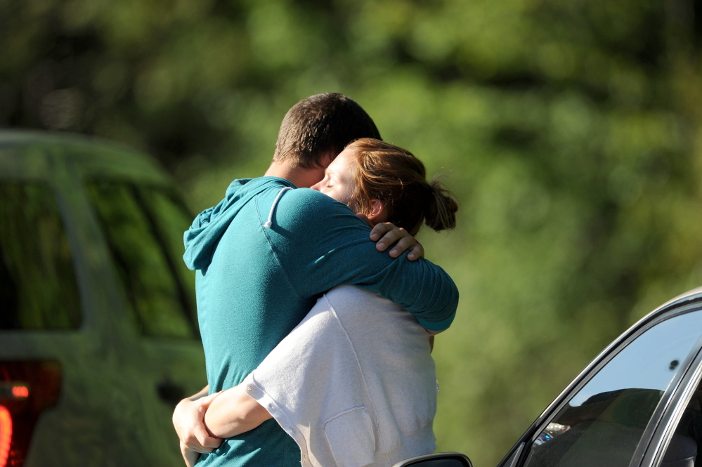 Staff photo by Michael G. Seamans
A couple from Canada hug after witnessing a logging truck flip and hit an SUV on U.S. Route 201 in Moscow on Thursday.