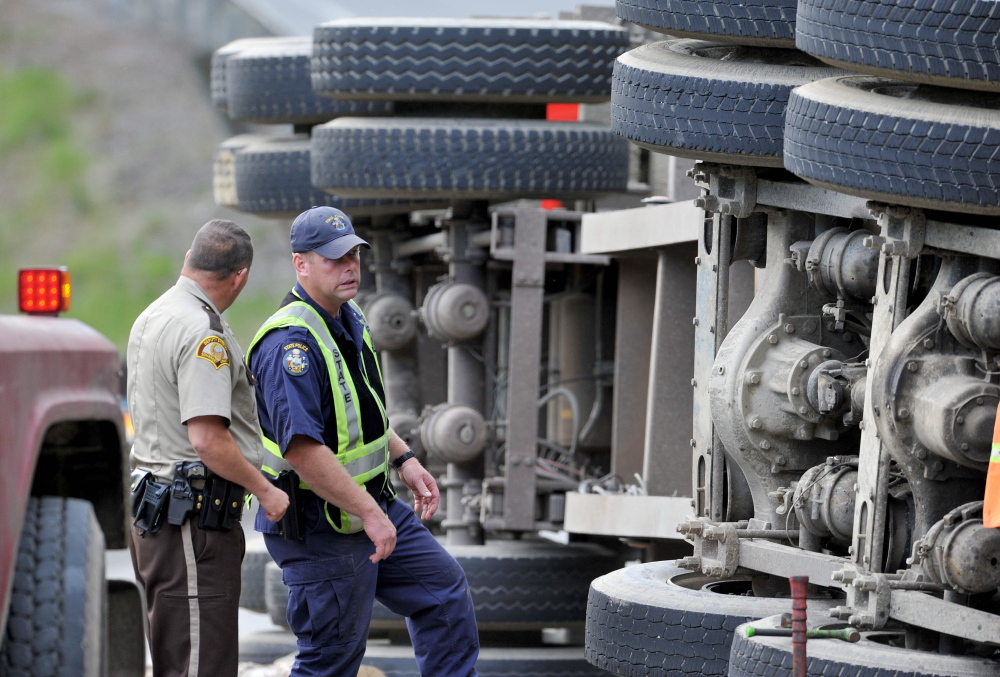 Staff photo by Michael G. Seamans 
 Investigators inspect a logging truck that flipped and hit an SUV on US Route 201 in Moscow on Thursday, June 26, 2014. Two adults and baby from the SUV were transported to the hospital by ambulance with unknown injuries and a third adult from the vehicle was transported by LifeFlight.  The truck driver was also transported to the hospital.