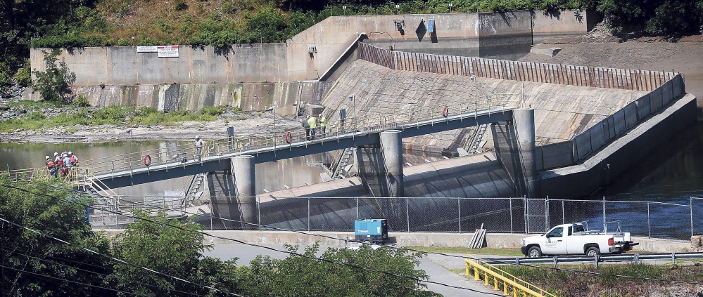 Workers stand atop the Brookfield Dam over the Kennebec River between Winslow and Waterville. The dam is one of four owned by Brookfield Power US Asset Management that are the subject of a lawsuit by environmental groups seeking to protect Atlantic salmon. A federal appeals court Monday revived part of the lawsuit that was dismissed last year.