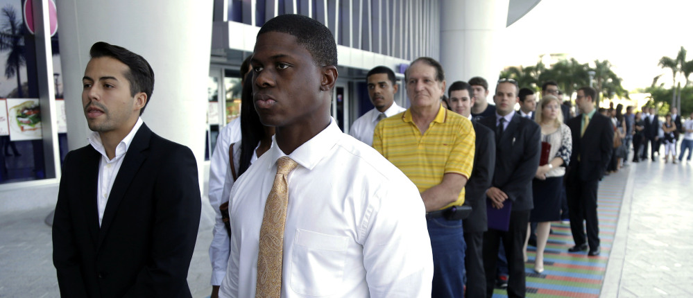 People seeking work wait in line at a job fair in Miami last October. The decline in long-term unemployment between 2014 and 2013 likely means that while some of the long-term unemployed have found jobs, more have stopped looking at all – removing them from unemployment figures.