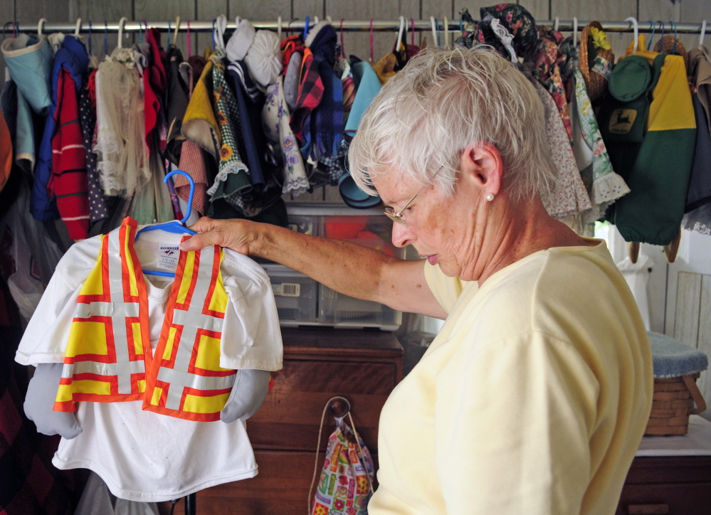 Staff photo by Joe Phelan
Sally Kinkade hangs up one of the about 100 outfits that her mother Marjorie Scott has for the concrete goose on Wednesday in Augusta. Scott has been dressing up Georgie the Goose that stands in front her Eastern Avenue home for 20 years. This construction flagger outfit was made in honor of gas pipeline construction that was going on along Eastern Avenue last year.