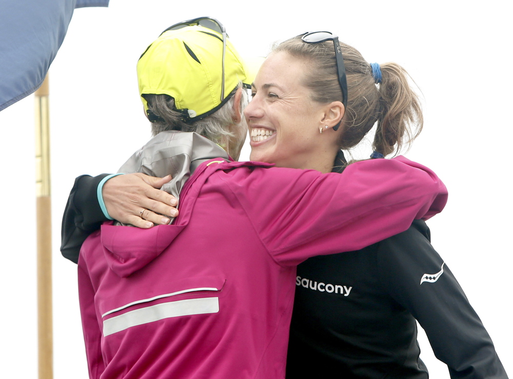 Michelle Lilienthal of Portland receives a hug from Joan Benoit Samuelson after setting a course record for Maine women in 33:38.8 at the TD Beach to Beacon 10K in Cape Elizabeth on Saturday.